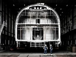 Workers inspecting large superyacht structure in hall of Project 410 the largest sloop yacht