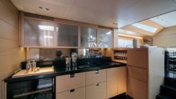 WallyWind110 Modern yacht kitchen with wooden cabinets and appliances.