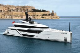 60m Motor Yacht CRN Comfortably Numb. Luxury yacht sailing near historic city coastline.