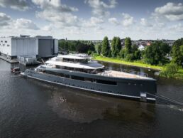 Feadship Project 713 Superyacht. Large yacht near shipyard building on river