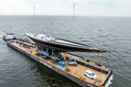 Hanuman Yacht Refit. Large J-Class yacht transported on platform in wind turbine sea