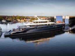 Luxury yacht ONE by Feadship docked near shipyard entrance.